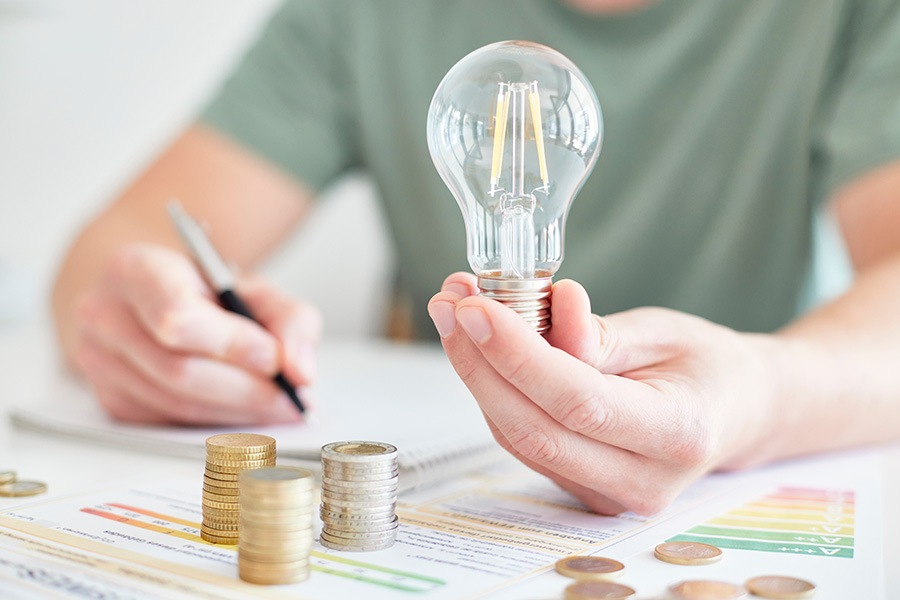 Mann hält Glühbirne neben Energieausweis